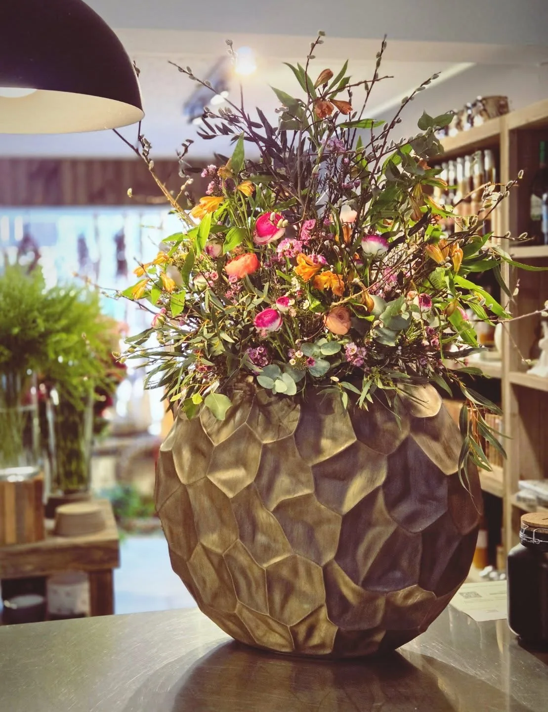 Großes florales Arrangement mit Zweigen und farbenfrohen Blüten in einer dekorativen Vase