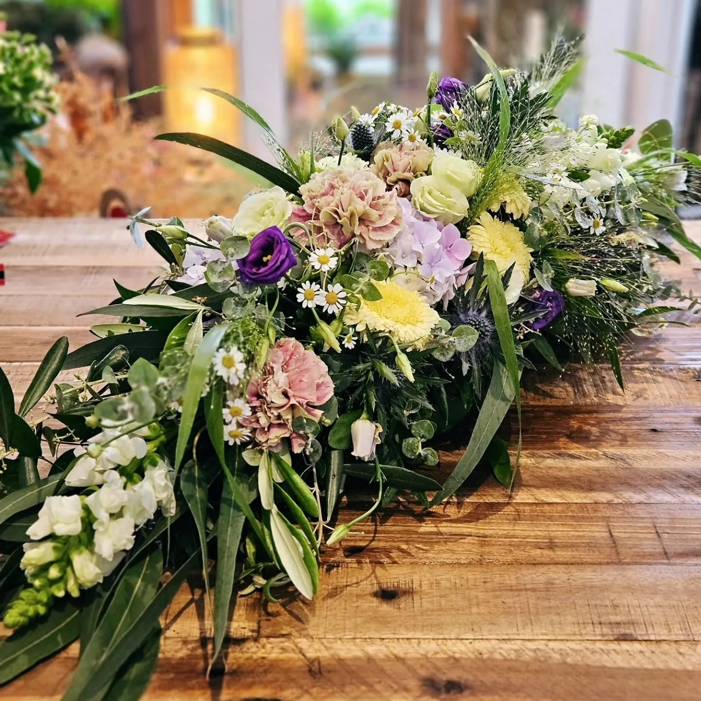 Lockere florale Tischdekoration in Pastelltönen mit Hortensien, Nelken, feinen Blüten und Eukalyptus