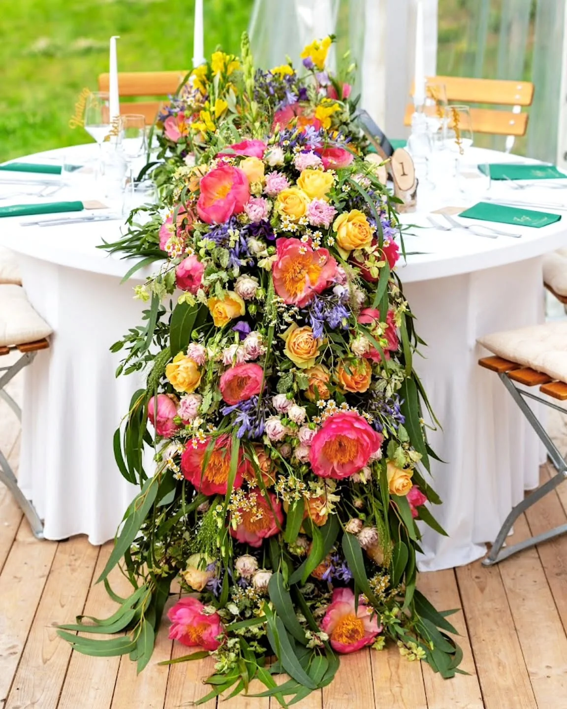 Farbenfrohe florale Tischdekoration für eine Hochzeit mit Pfingstrosen und Rosen