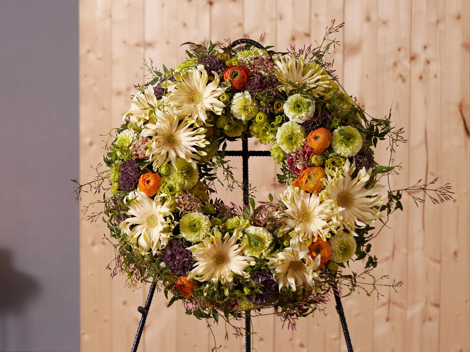 Natürlicher Trauerkranz mit cremefarbenen Blüten, Grün und orangefarbenen Akzenten